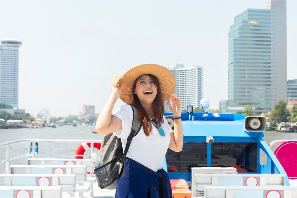 A woman tours Bangkok aboard a water taxi