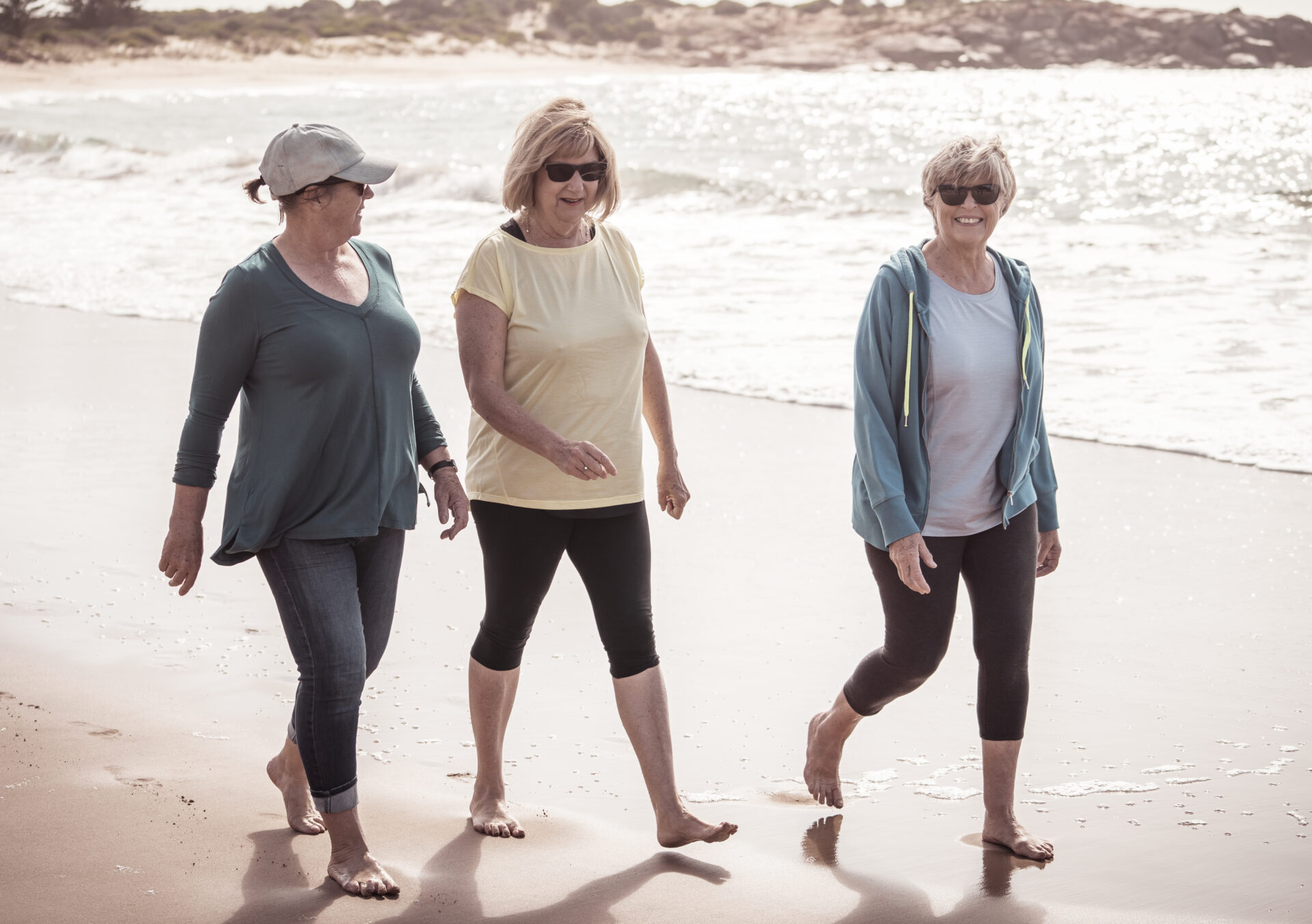 Three retiree expat women take a morning walk on a beach