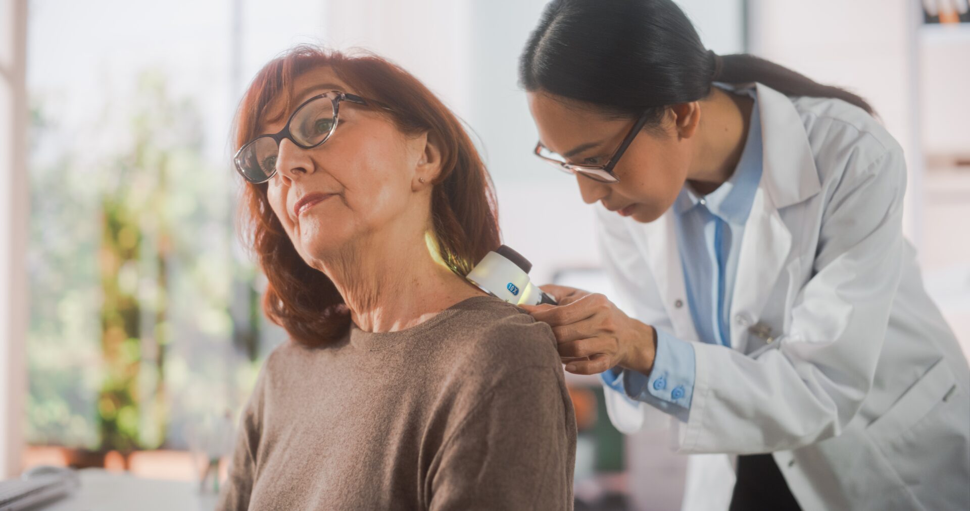 An older white woman gets a medical checkup from a young Thai doctor