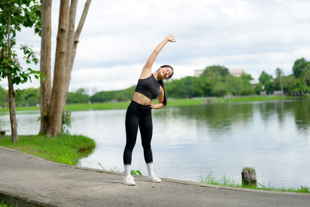 Runner warming up before a run through a shaded park path near Silom, Bangkok.